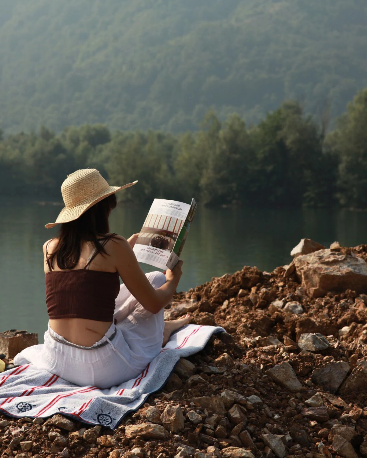 marija sedi na obali Zvornickog jezera i cita casopis, okrenuta ledjima